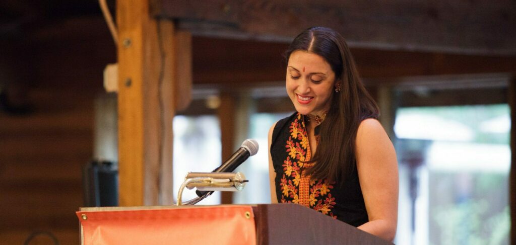 Sapna speaking behind a podium